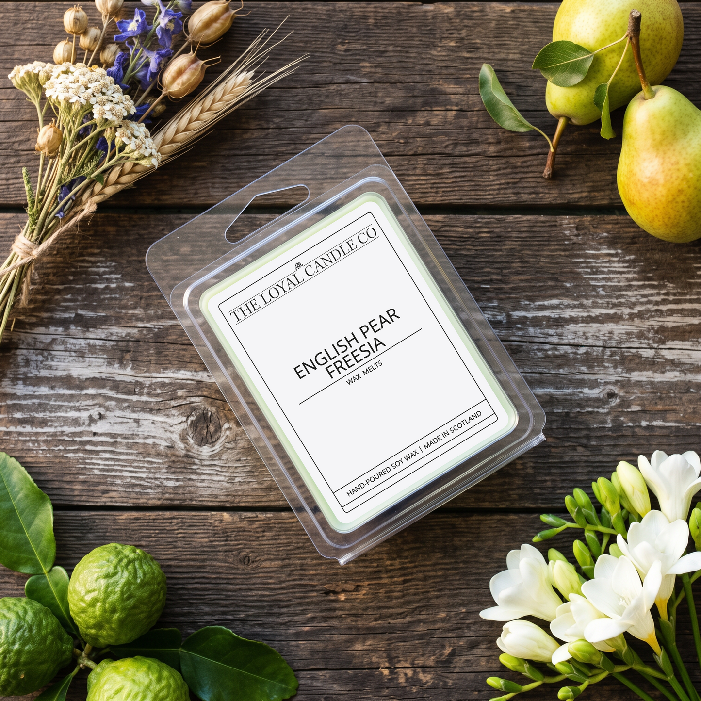 English Pear Freesia wax melt clamshell on a dark wood background.