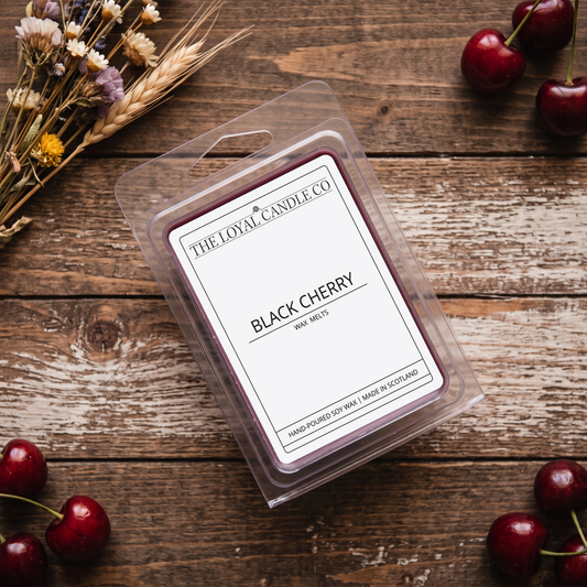 Black Cherry wax melt clamshell on a dark wood background with dried wheat sprigs