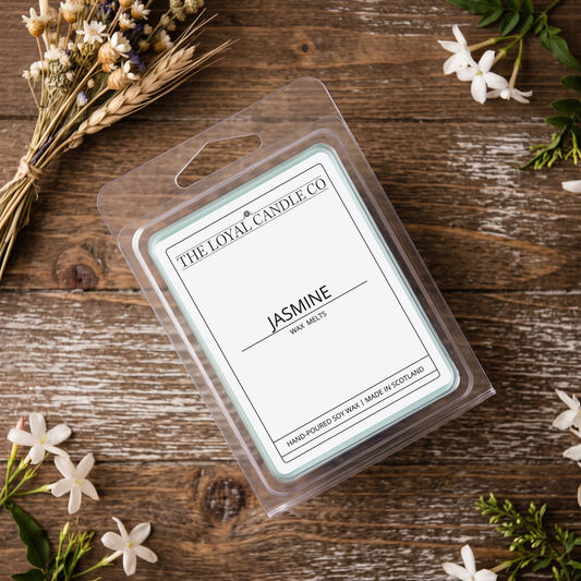 Jasmine wax melt clamshell with fresh flowers on a dark wood background.