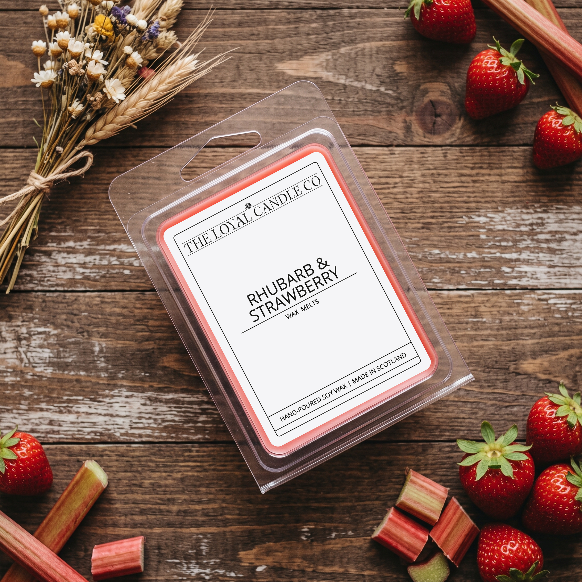 Rhubarb & Strawberry wax melt clamshell with fresh strawberries on a dark wood background.