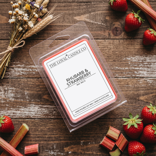 Rhubarb & Strawberry wax melt clamshell with fresh strawberries on a dark wood background.