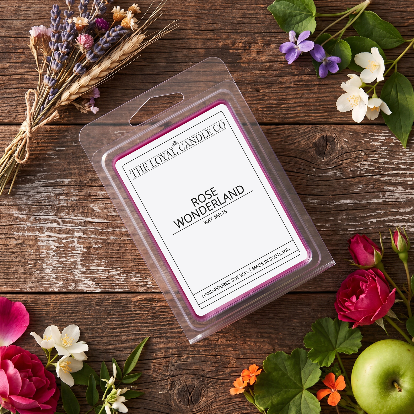 Rose Wonderland wax melt clamshell with dried roses on a dark wood background.